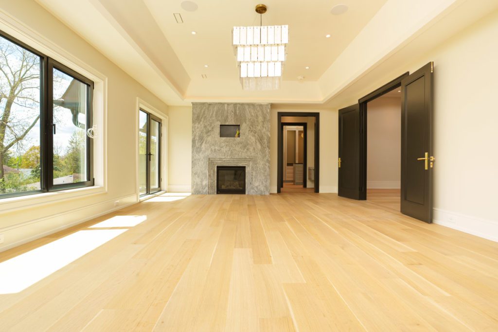 Large empty bedroom with light colored hardwood floors and a large window. Designed by Oakland Flooring in Richmond Hill.